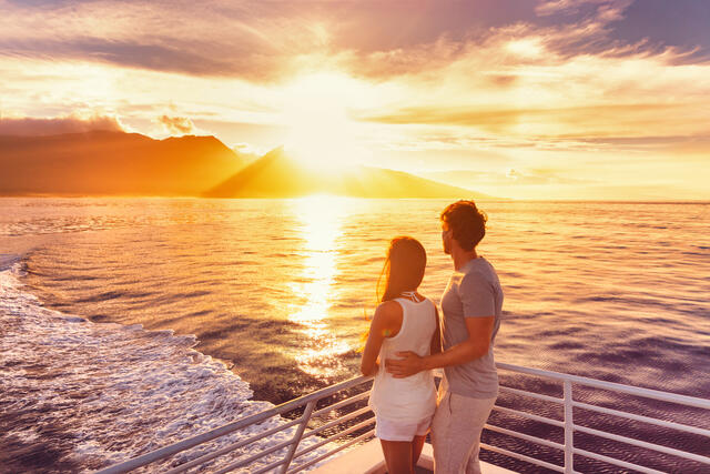 Travel cruise ship couple on sunset cruise in Hawaii holiday. Two tourists lovers on honeymoon travel enjoying summer vacation.